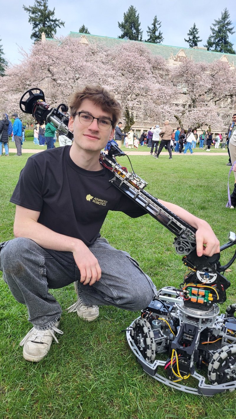 Casey Frantz kneeling with the ARC robot on the University of Washington campus